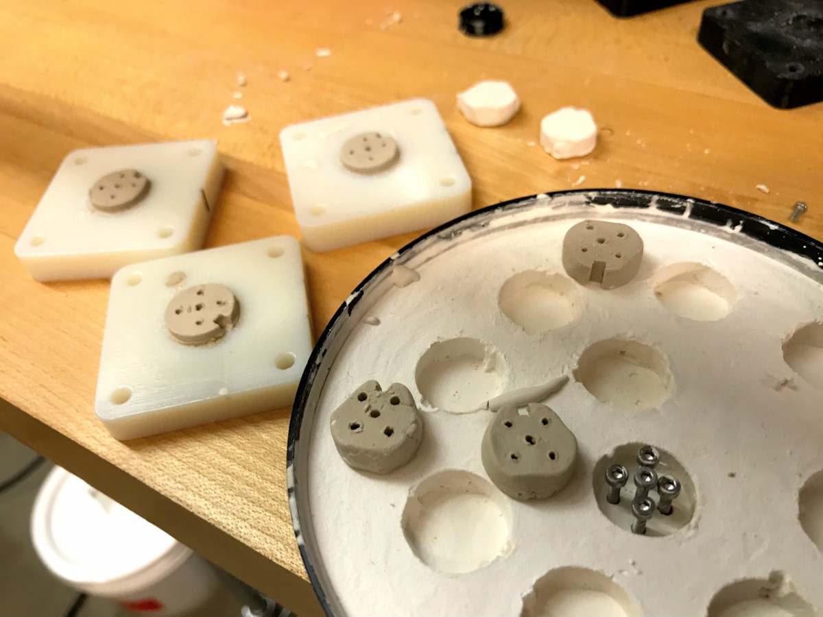 These bases are cast in slip using the plaster mold, and will be cleaned up by hand prior to baking.